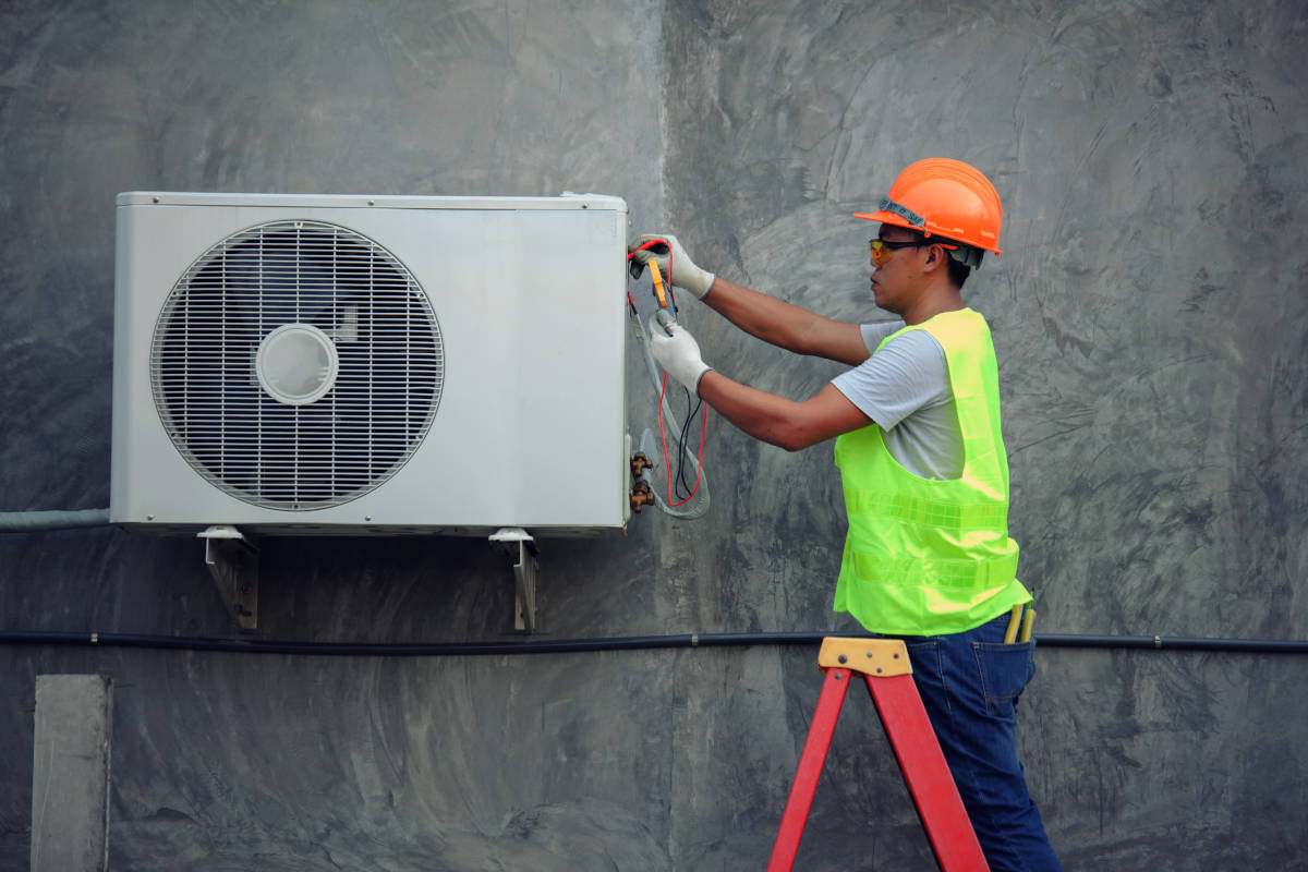 Refrigerista realizando manutenção em unidade condensadora de sistema de ar condicionado de pequeno porte (split) | Foto: Shutterstock