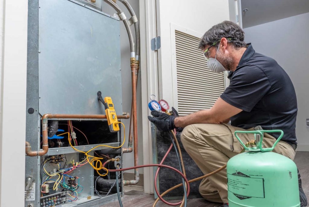 Técnico em refrigeração e ar condicionado reparando sistema de climatização | Foto: Shutterstock