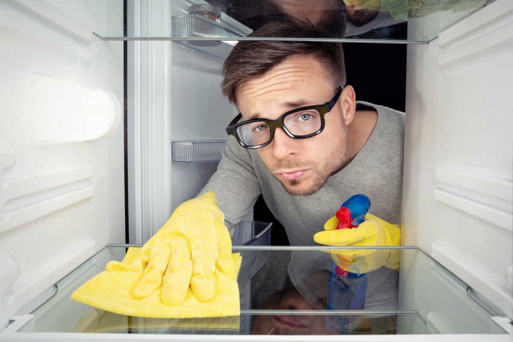 Homem limpando geladeira | Foto: Shutterstock