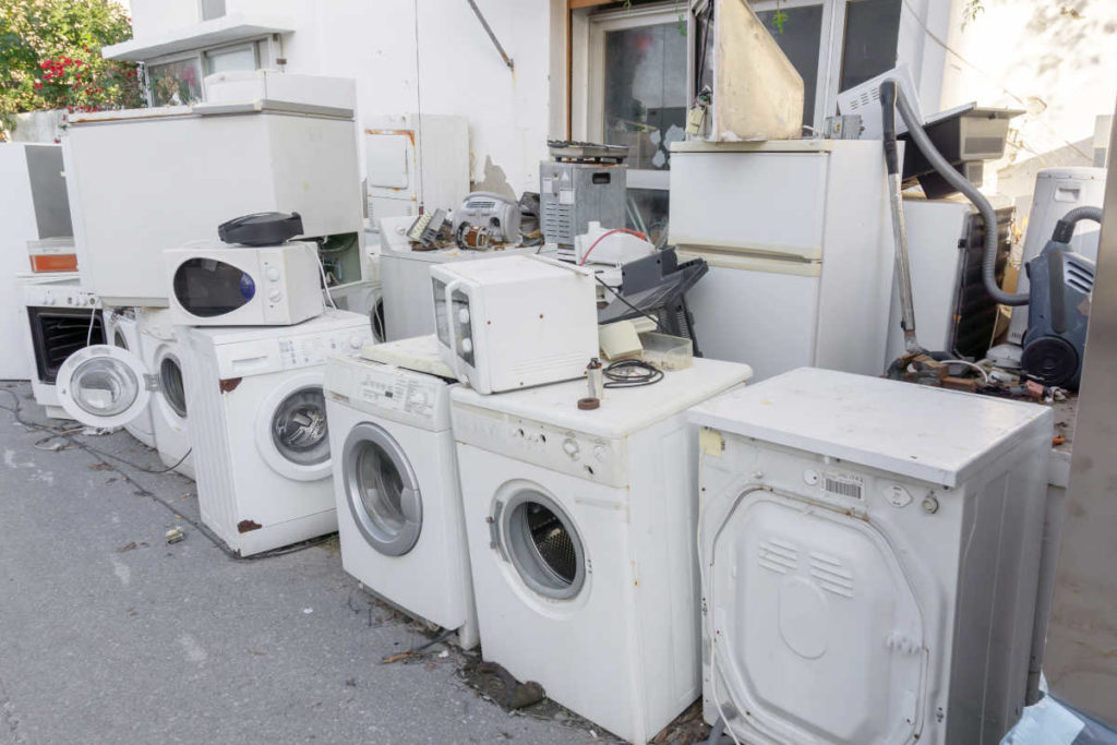 Lixo eletrônico composto por geladeira, freezer, micro-ondas e máquina de lavar disposto ao ar livre | Foto: Shutterstock