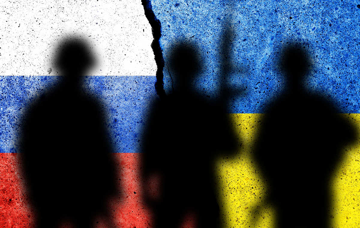 Sombras de militares armados sobre bandeiras da Rússia e Ucrânia pintadas em muro | Foto: Shutterstock