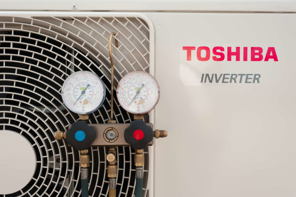 Condensadora de condicionador de ar fabricado pela Toshiba com manifold pendurado na máquina | Foto: Yurii Klymko/Shutterstock