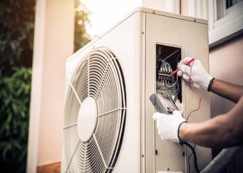 Refrigerista checando circuito elétrico em unidade externa de sistema de ar condicionado split | Foto: Shutterstock