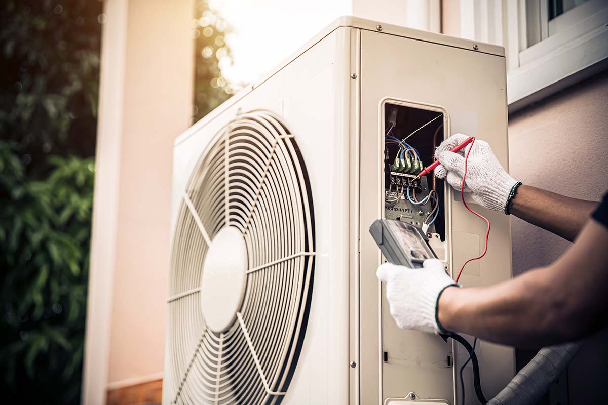 Refrigerista checando circuito elétrico em unidade externa de sistema de ar condicionado split