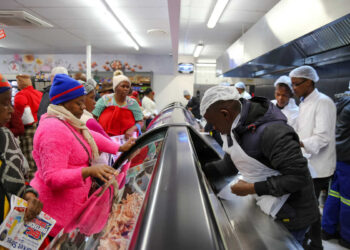 Vitrine de alimentos refrigerados rodeada por consumidores e atendentes de supermercado em Joanesburgo, na África do Sul | Foto: Africanstar/Shutterstock