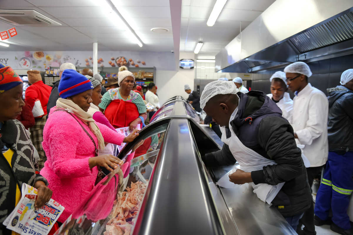 Vitrine de alimentos refrigerados rodeada por consumidores e atendentes de supermercado em Joanesburgo, na África do Sul | Foto: Shutterstock