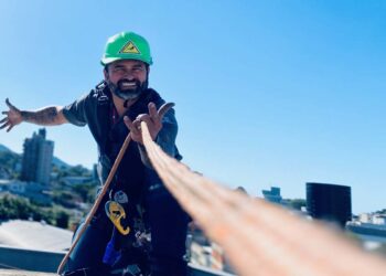Instalador de ar-condicionado especializado em alpinismo industrial em telhado preparando equipamentos de rapel