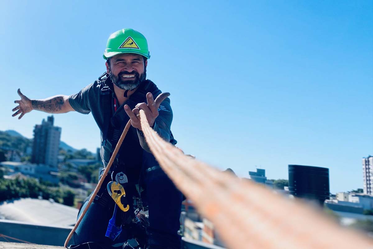 Instalador de ar-condicionado especializado em alpinismo industrial em telhado preparando equipamentos de rapel
