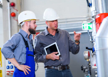 Profissionais da área de climatização inspecionando sistema de ar condicionado | Foto: Shutterstock