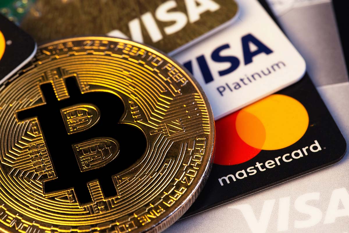 Criptomoeda Bitcoin com closeup de cartões eletrônicos de plástico Visa e Mastercard | Foto: Primakov/Shutterstock