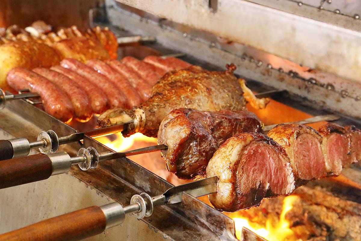 Carnes sendo preparadas no espeto em churrasqueira | Foto: Shutterstock